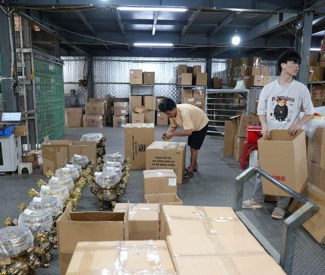Two workers boxing finished bronze into cartons printed with the foundry's own fragile-handling marks