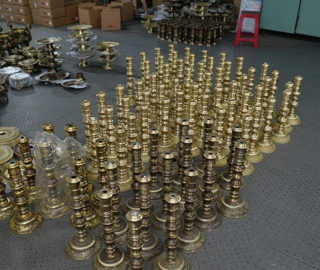 Finished bronze candlesticks staged in rows on the workshop floor