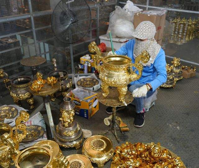 Gold leaf being laid onto a censer at the gilding bench