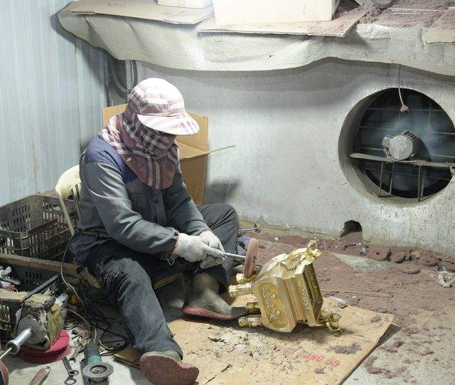 A finisher working a cast bronze piece by hand at the fettling bench