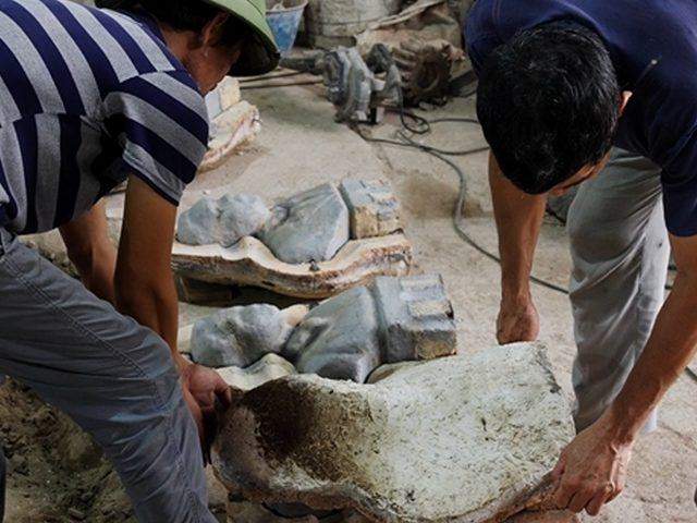 Two workers breaking open a fired mould to free the rough castings inside