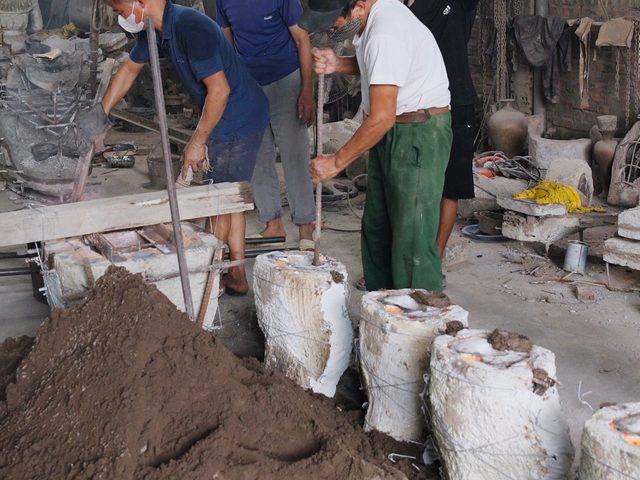 Casters ramming sand around poured moulds, runners still glowing